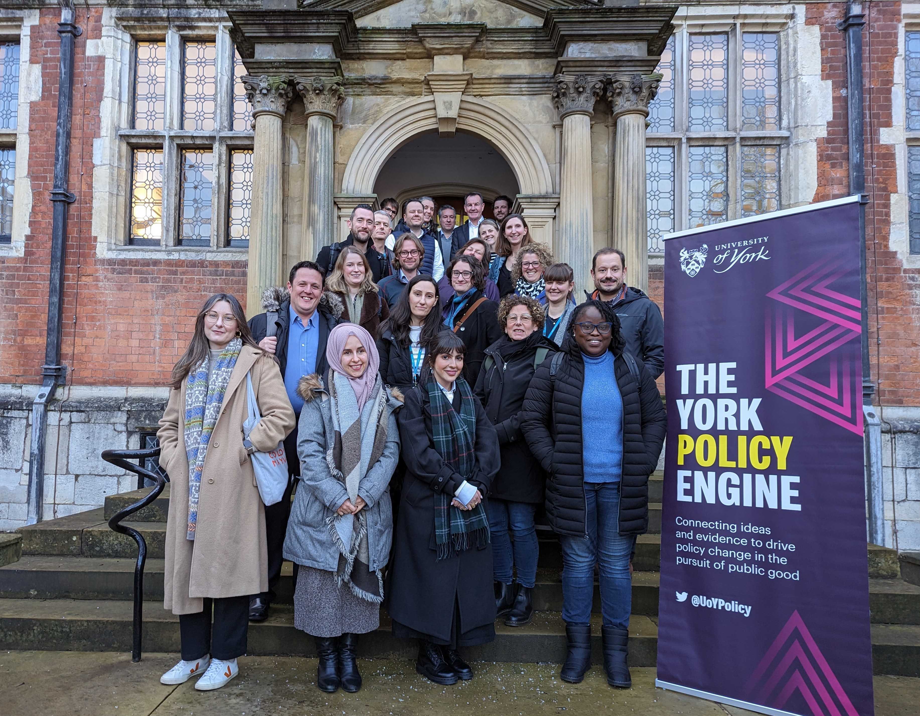 A group of people standing together on the stairs at Heslington Hall